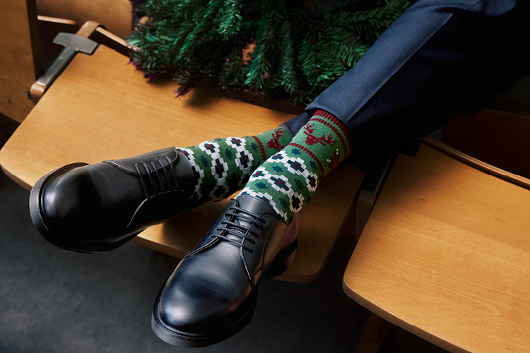 Nahaufnahme von Herrenfüßen mit Burlington Weihnachtssocken in Anzugschuhen